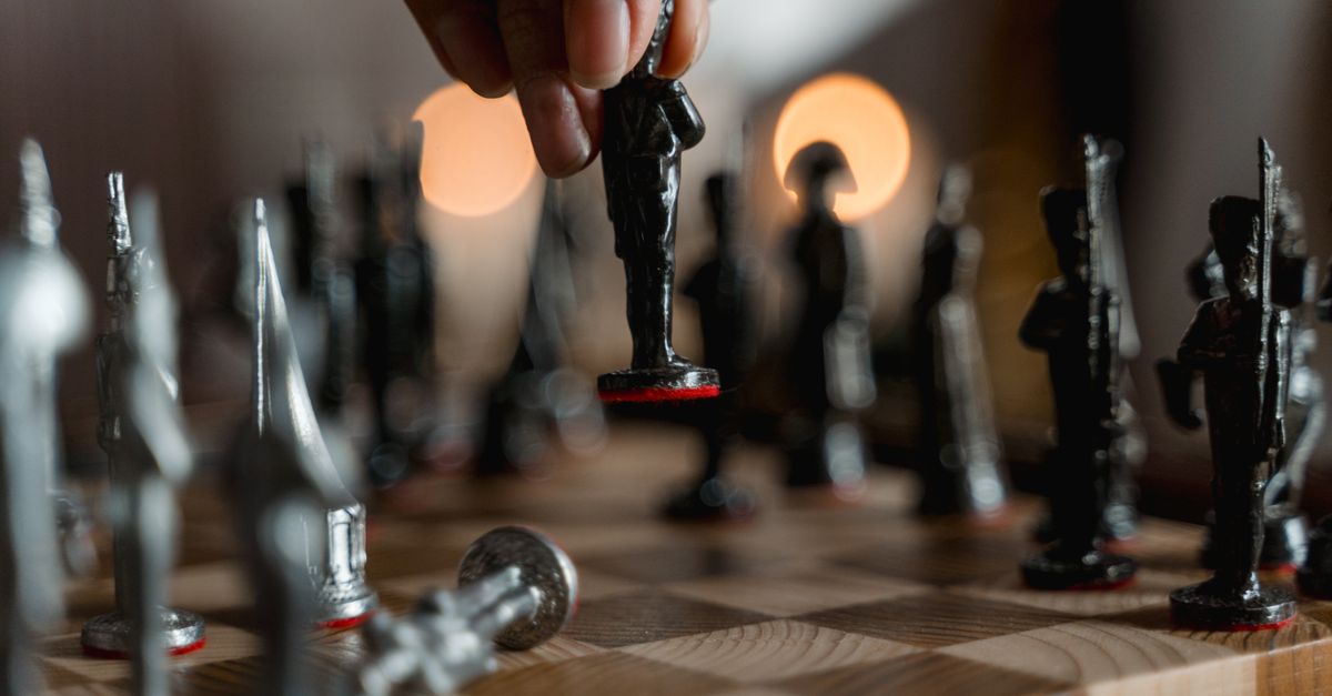 Hand placing unique chess piece on board, evoking strategy and intelligence.